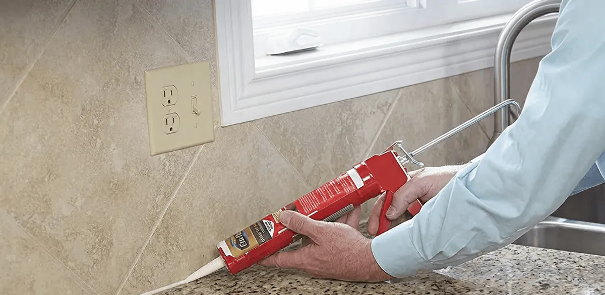 Handyman applying caulk along a kitchen backsplash and countertop seam in Nashville, TN